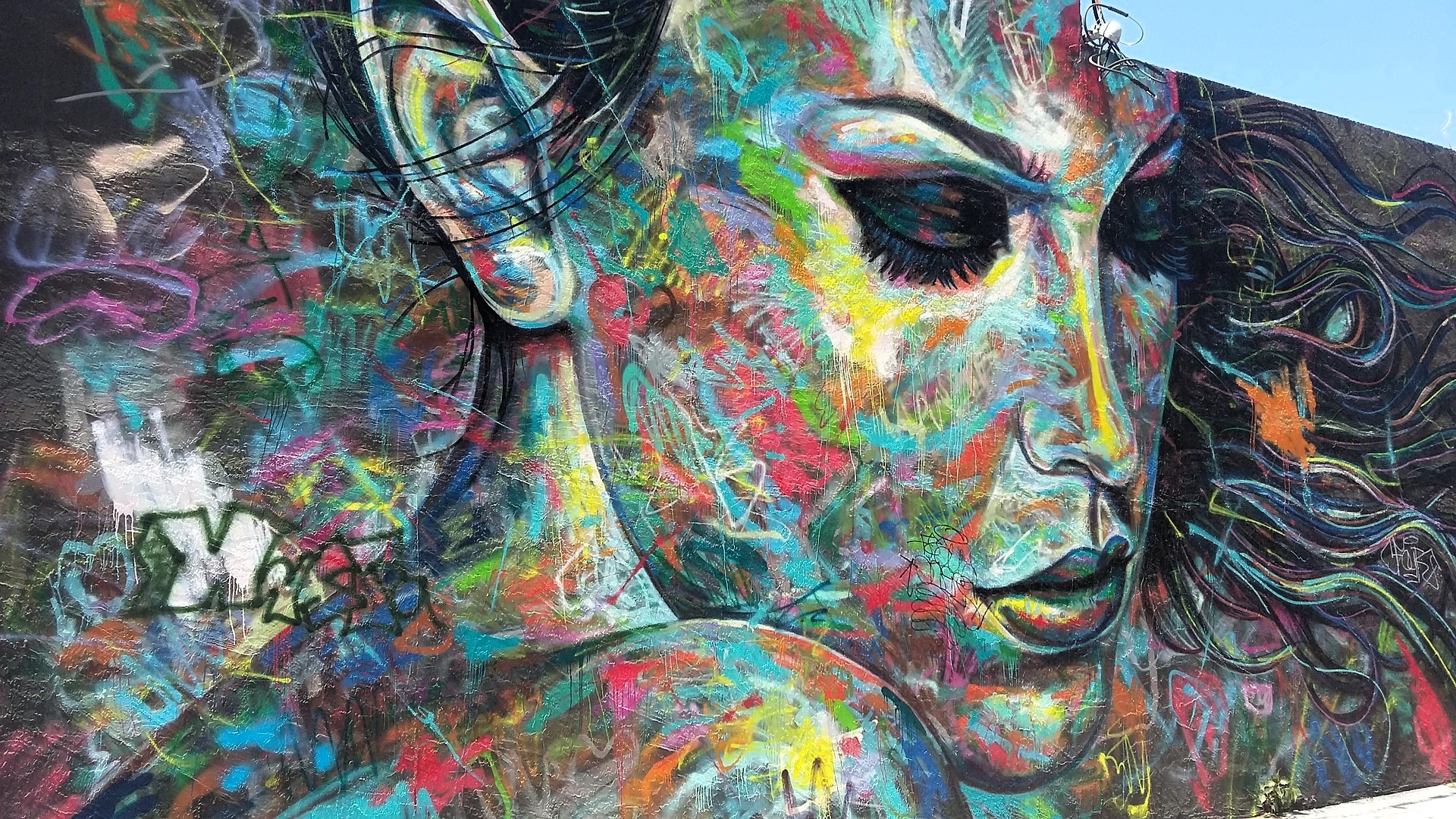 Mural urbano multicolor de rostro femenino, estilo graffiti, que evoca introspección y calma interior.