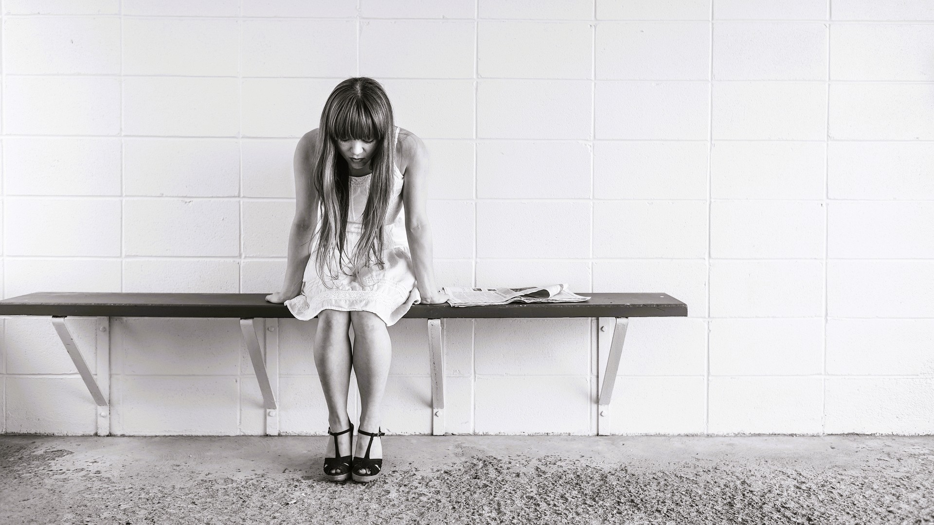 Mujer sentada con gesto de ansiedad; meditación guiada y respiración consciente.