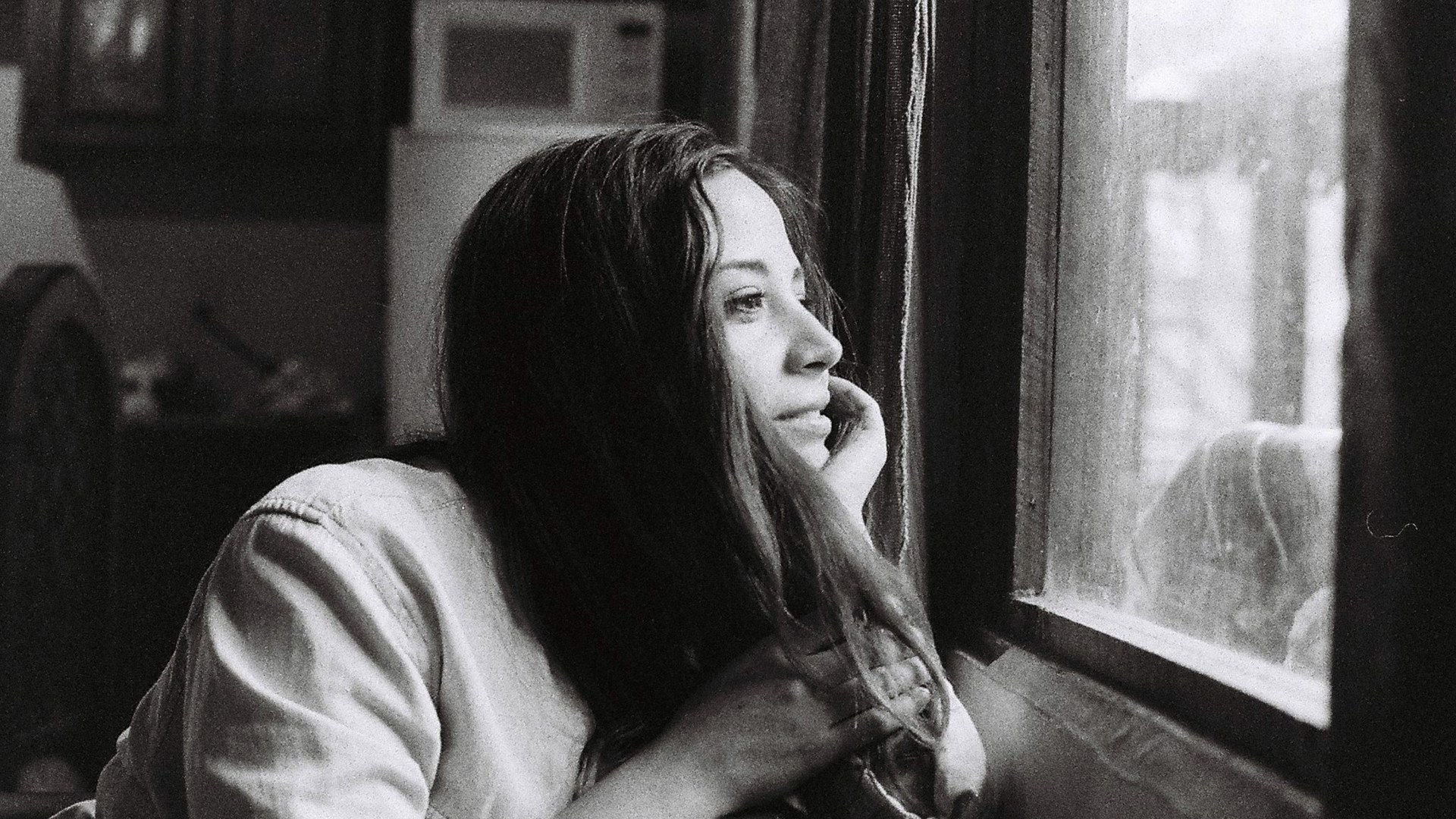 Mujer pensativa mirando por la ventana, simbolizando la manifestación consciente y la introspección personal