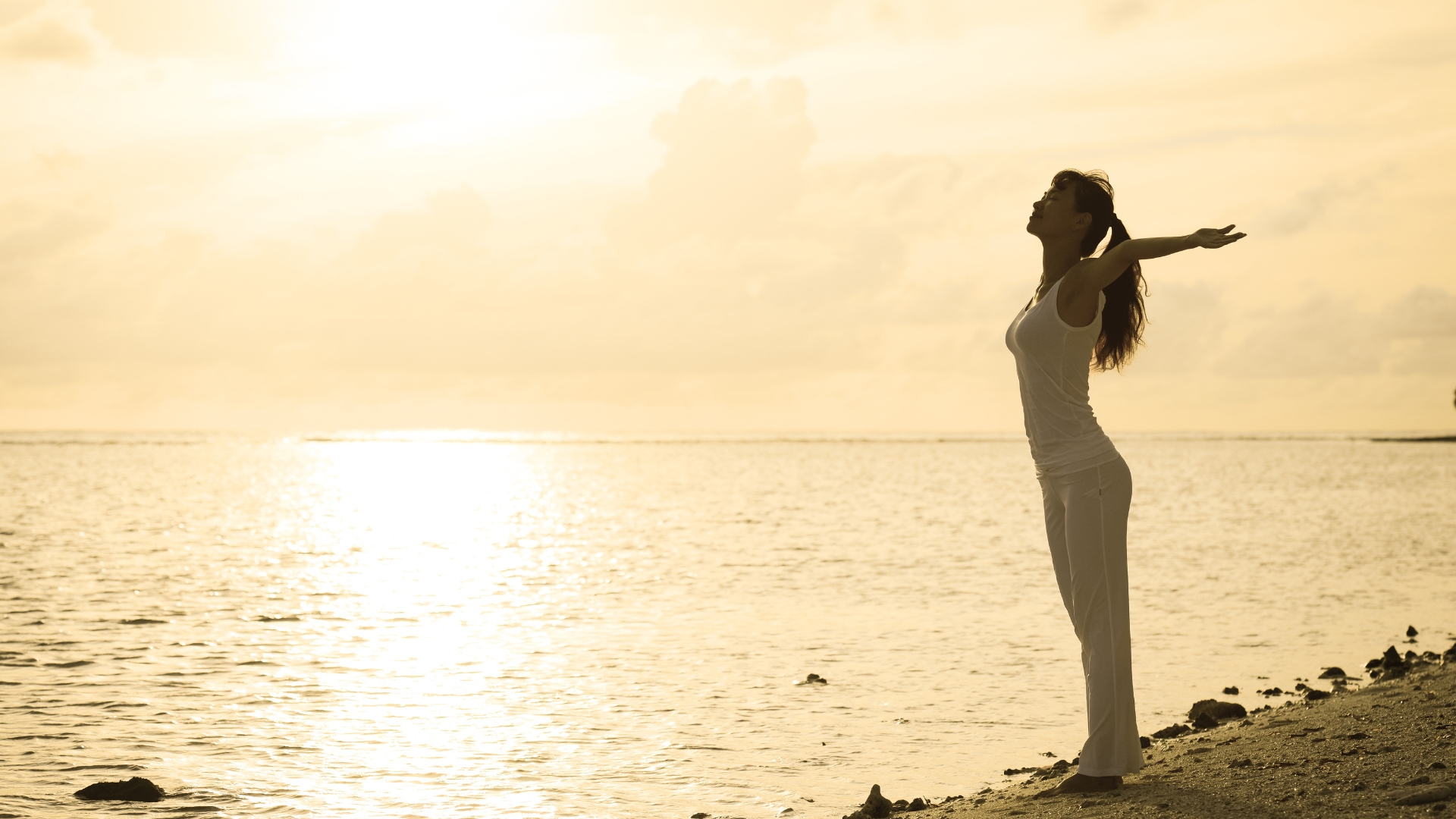 Mujer respirando frente al mar al amanecer, símbolo de calma y regulación del sistema nervioso